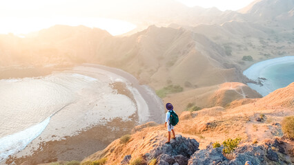 Travel man stand on the top and looking beautiful sunrise at Padar island in Komodo National Park,...