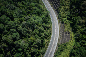 Aerial view of asphalt road with cars through green forest woods and mountain, Trang, Thailand.