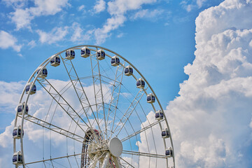 Ferris wheel with cabins set against blue sky. Leisure and amusement park fun