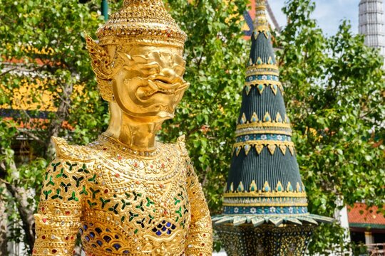 Asurapaksi, a gold giant-and-bird chimera statue beside a panom mak (banana leaf offering) sculpture at the Temple of the Emerald Buddha (Wat Phra Kaew) inside the Grand Palace - Bangkok, Thailand 