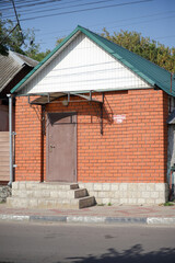 A small brick building with a red roof and white trim