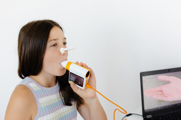 Girl testing breathing function by spirometry in doctors office. Diagnosis of respiratory function...