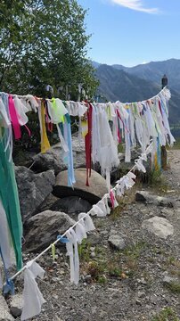 Vertical video of Religious buddhist prayer flags in Altai Chiketaman mountain pass. Flags are flutter in the wind on blue sky and moutains on background.