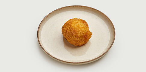 A crispy and golden-brown Kyiv-style chicken cutlet is presented on a beige plate against a clean white background. The cutlet is filled with herb butter and breaded to perfection.