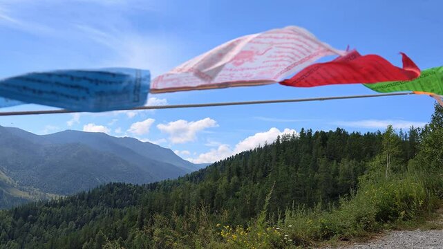 Slow motion video of Religious tibetan buddhist prayer flags in Altai Chiketaman mountain pass. Flags are flutter in the wind on blue sky and moutains on background.