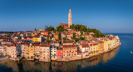 Rovinj, Croatia - Aerial panoramic view of the old town of Rovinj with Church of St. Euphemia on a summer morning in Istria, Croatia. Clear blue sky and warm morning lights by the Adriatic sea
