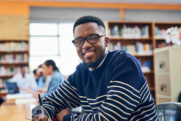 Obraz premium Black man, student and smile in portrait, library and writing notes for learning, development and research. Person, happy and pride with education, scholarship and studying at university in Nigeria