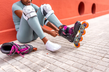 Woman putting on inline skates sitting on the street