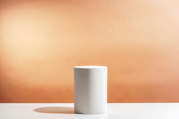 Minimalistic display of a white cylindrical object against a soft orange background