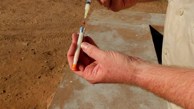 Caucasian veterinarian injects syringe with drugs for dart gun, South Africa