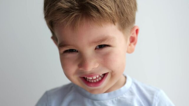 portrait of cute laughing little boy on grey background