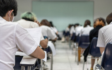 Exam with school students in class back view of the classroom of young people having stress doing examination admission test for university and college education background