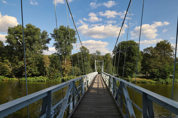 Weitwinkelperspektive auf der historischen H&auml;ngebr&uuml;cke &uuml;ber die Mulde mit Blick auf die Stahlkonstruktion und das bewaldete Flussufer, Grimma, Sachsen, Deutschland