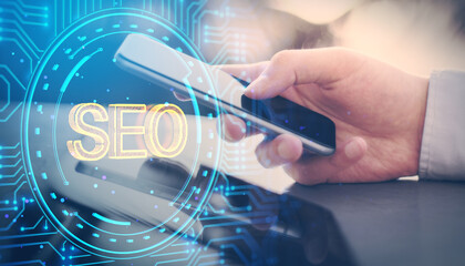 Close up of businessman hands using cellphone at desk with glowing digital data hologram on blurry blue background. SEO, big data and technology concept. Double exposure.