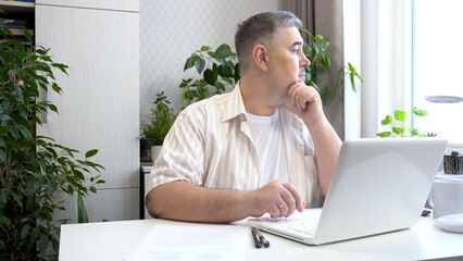 Freelancer Deep in Thought at Desk Looking Out of Window