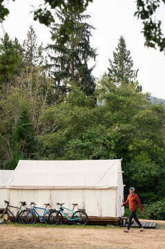 Man Walking Past Bicycles Near White Canvas Tent at Campground