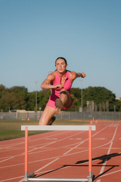 Female track athlete hurdling on track