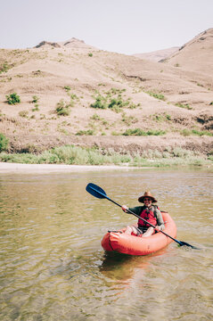 Adventurous Kayaker Explores Tranquil River Against Arid Hills
