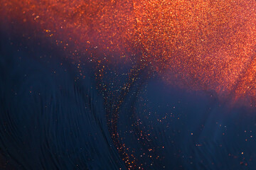 Colorful liquid paint abstract background. Red, blue and purple acrylic paints with shining golden glitter