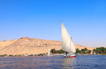 Traditional sailing boat felucca, Nile river near Aswan, Egypt. A famous tourist attraction -...