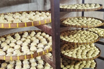 Raw steamed buns arranged in rows on a bamboo tray.