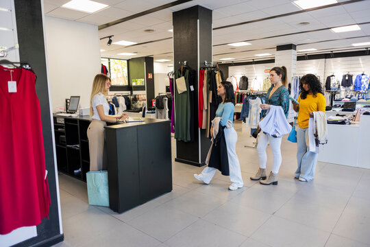 Cashier assisting customers waiting in line at fashion store