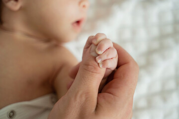 New born baby holding thumb of father