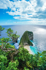 Man sits looking at the dramatic turquoise ocean with waves and green cliffs in Klingking Beach, Nusa Penida, Bali, Indonesia. summer background and summer vacation concept. © Balnyes Visuals