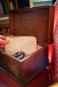 A woman takes a handwritten old letter out of an opened old wooden box representing memories and family history.