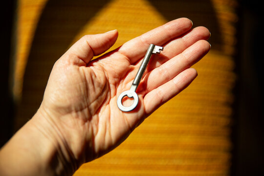 A woman holds an old key in her hand symbolizing genealogy and inheritance.