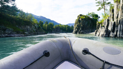 A boat is traveling down a river with a blue sky in the background. The water is calm and the trees...