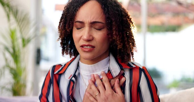 Woman, chest and pain with heart burn, asthma or panic attack from arrhythmia on sofa at home. Young, sick female person or breathing problems for anxiety, injury or cardiac arrest in stress at house