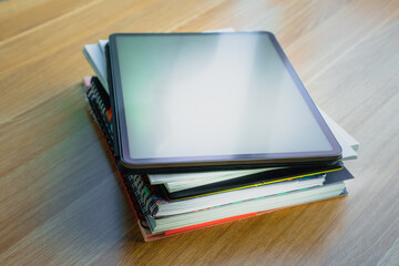 Books documents graphic tablet on top. Documents stack wooden table.