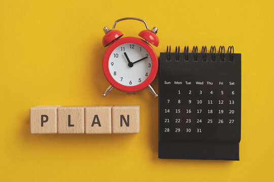 Wooden cube blocks  with plan text, red analog alarm clock and black calendar on yellow background for goal, reminder and action prepare to do the list , business strategy, vacation concept