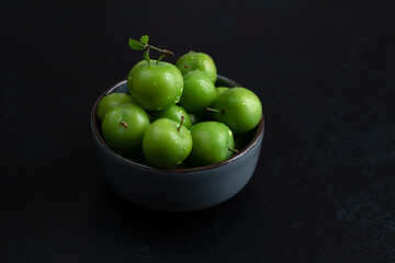 Green plum fruit in ceramic bowl on white background, fruit that pregnant women love