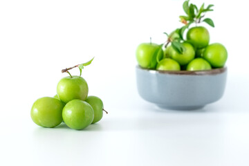 Green plum fruit in ceramic bowl on white background, fruit that pregnant women love