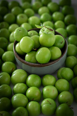 Green plum fruit in ceramic bowl on white background, fruit that pregnant women love