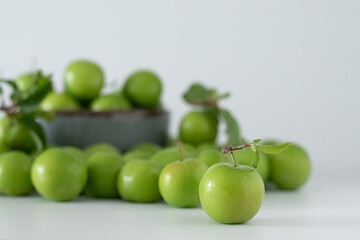 Green plum fruit in ceramic bowl on white background, fruit that pregnant women love