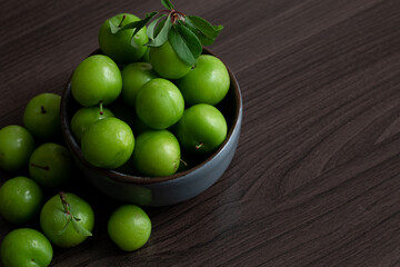 Green plum fruit in ceramic bowl on white background, fruit that pregnant women love