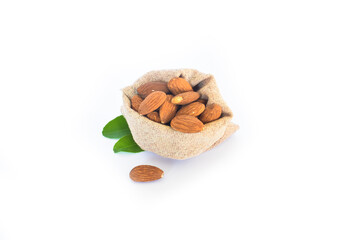 Title: A jute bag filled with organic Almond kernels (Prunus dulcis) is placed over a pile of Almonds, isolated on a white background.