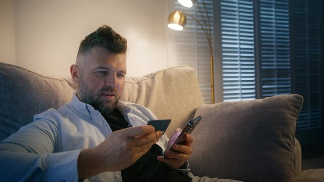 A man is diligently focused on entering his credit card details into his smartphone for a secure online purchase, carefully ensuring the transaction process is smooth and free of any issues