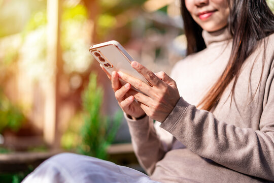 Young female using mobile phone and relaxing in the garden, Modern lifestyle