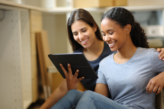 Happy couple checking tablet while moving home