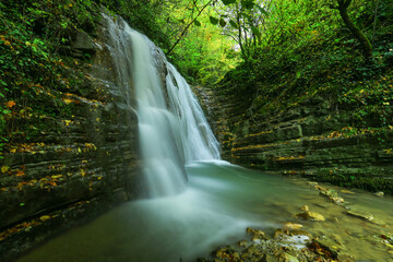 Obraz premium image of waterfall, lake and rock formations among autumn colors.