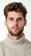 Obraz premium A stylish young man with blue eyes and a beard wearing a cozy sweater, portraying confidence and charm in a neutral setting.