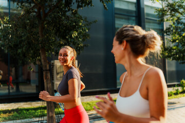 Caucasian sisters running outdoors, smiling and bonding through their fitness routine.