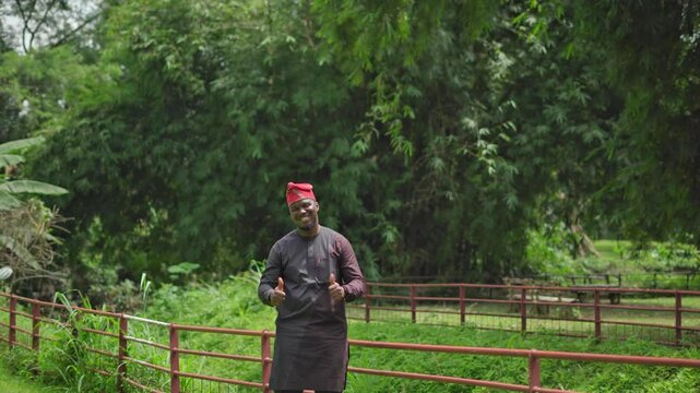 African Nigerian Yoruba outdoors turns and gives thumbs up with a big smile.
