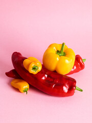 Pile of bell and long sweet peppers over pink background