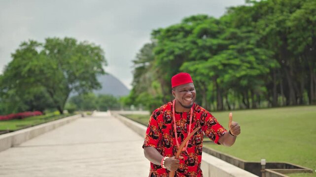 Igbo man wearing the traditional Isiagu attire celebrates a win with screams and thumbs up.
