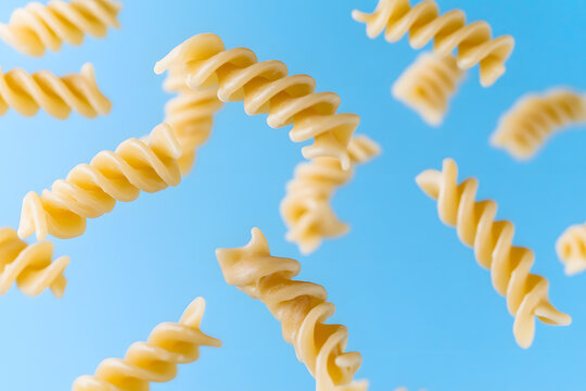Dry pasta swirling in the air on blue background